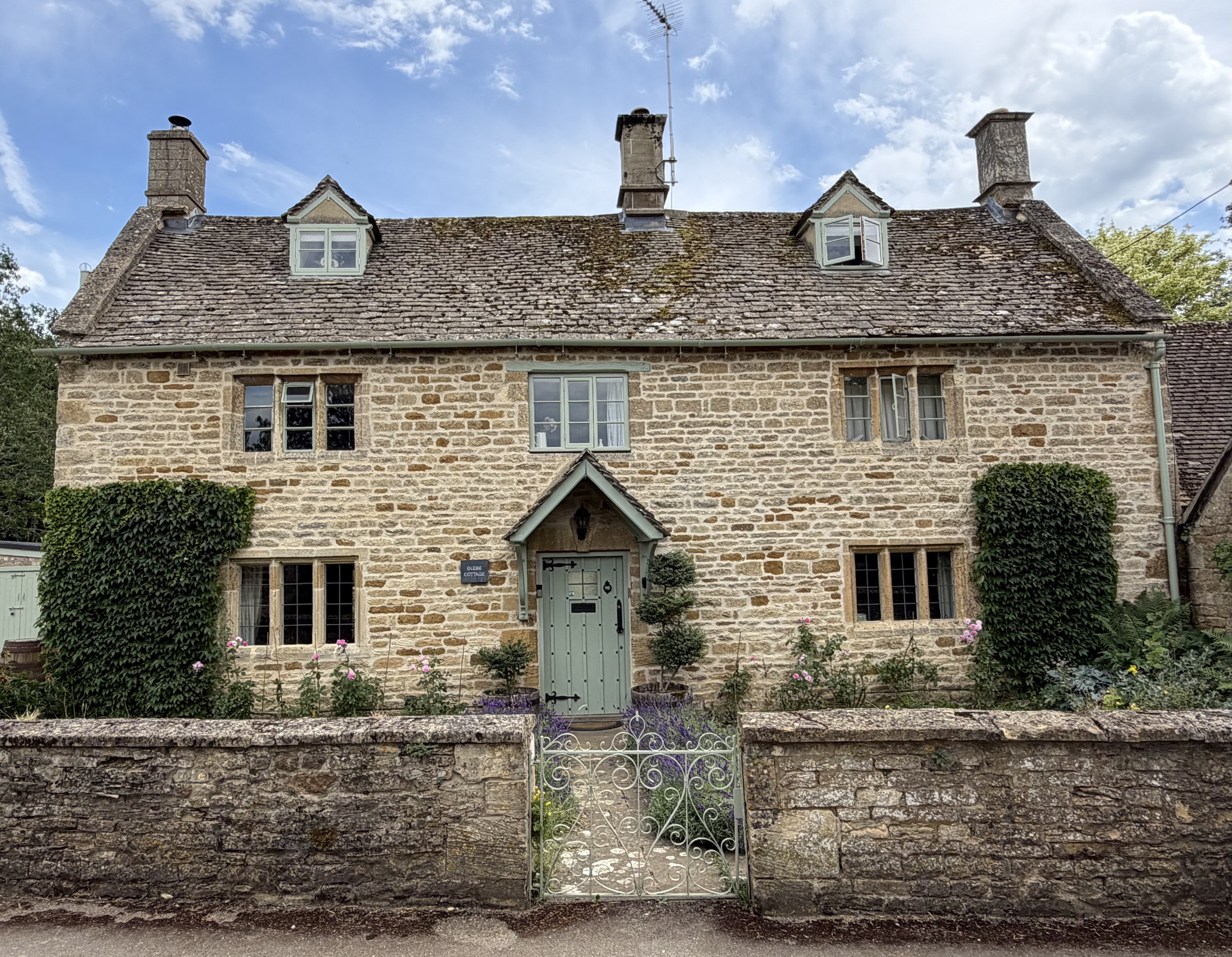 Front elevation of Glebe Cottage, a Grade II listed Cotswold stone holiday cottage in Bledington, Oxfordshire