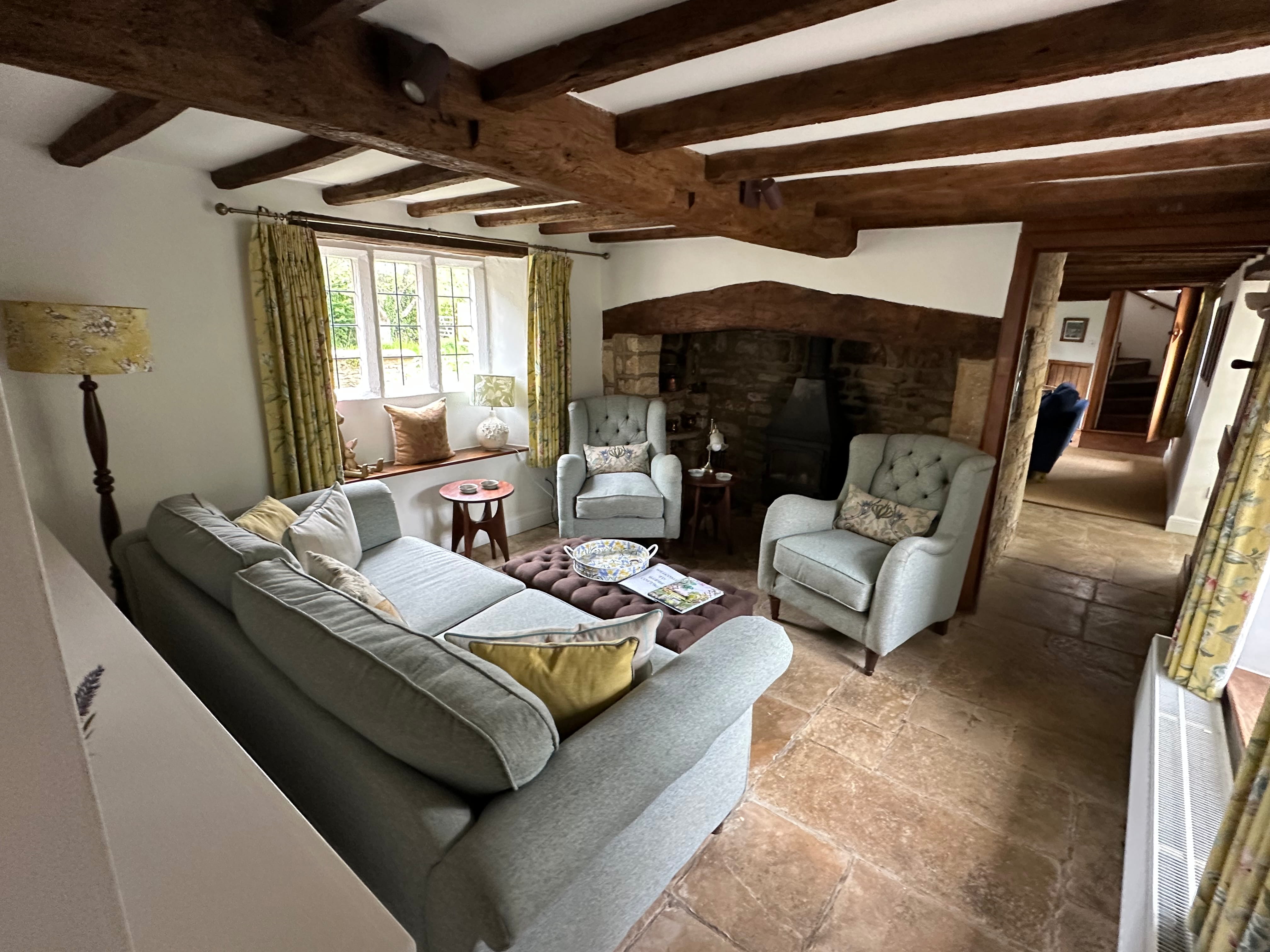 Cosy living room with wood burning stove at Glebe Cottage, a Grade II listed holiday cottage in Bledington, Cotswolds