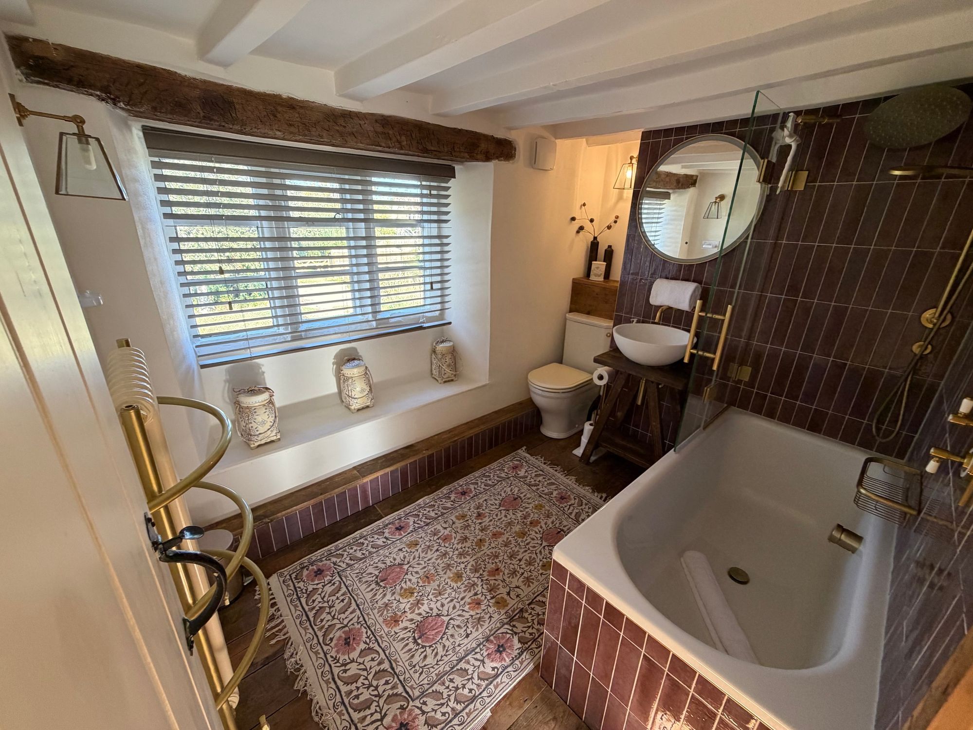 Main bathroom with bath, shower and brass fittings at Glebe Cottage, Bledington