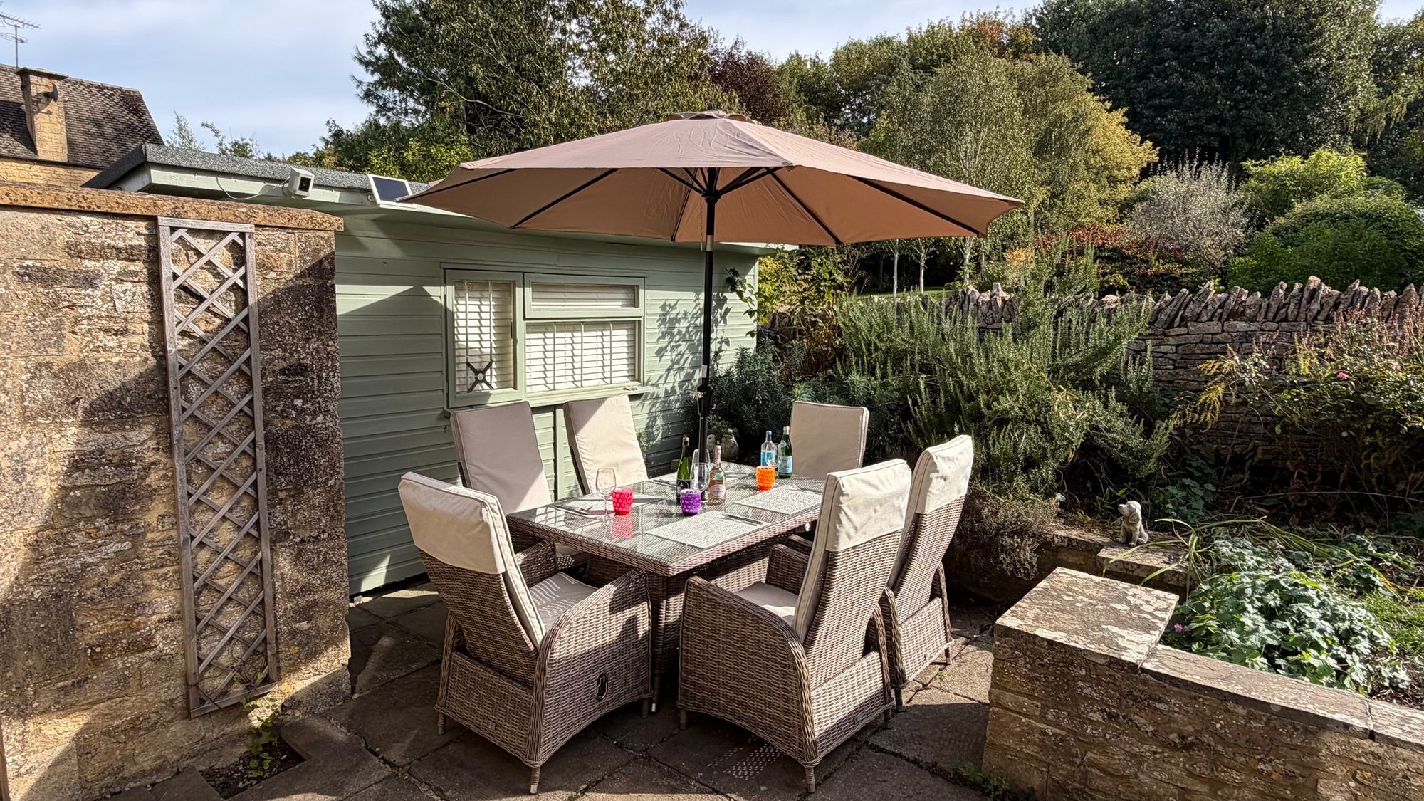 Patio dining table and chairs with the umbrella up at Glebe Cottage, Bledington